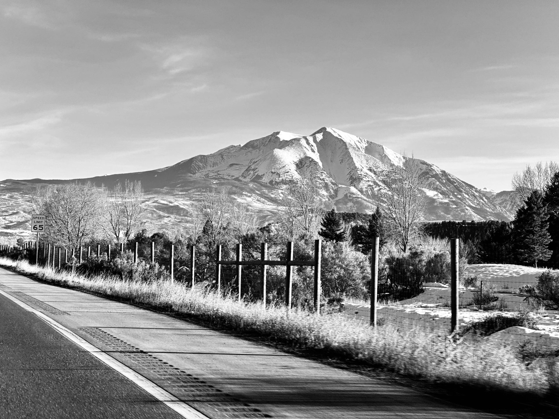A black and white photo of a road with mountains in the background